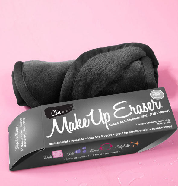 Rolled up Chic Black MakeUp Eraser with box on a pink surface sprinkled with water