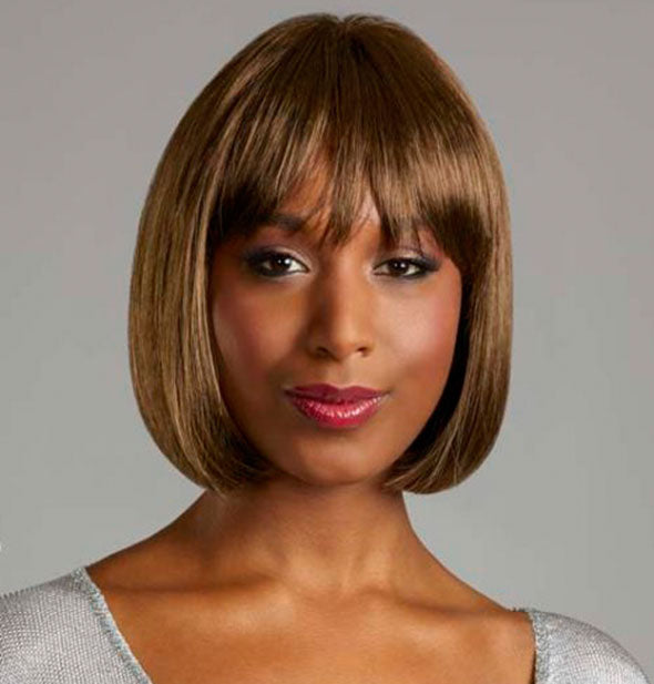 Model wearing a short, medium brown wig with bangs.