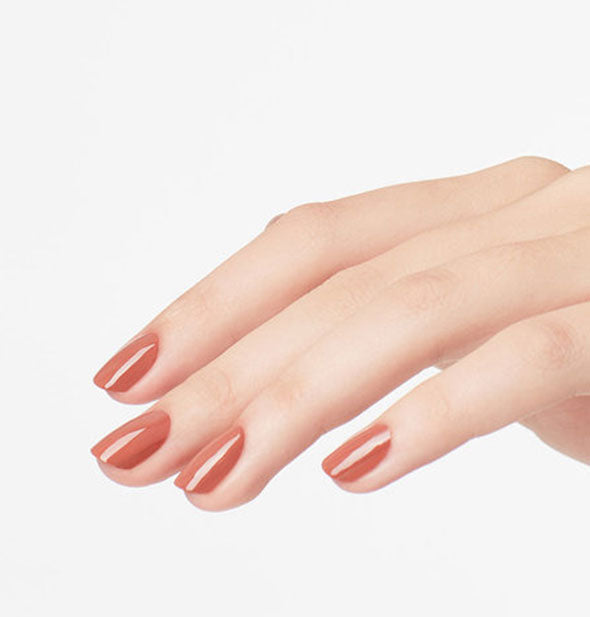 Model's hand wears a warm brown shade of nail polish