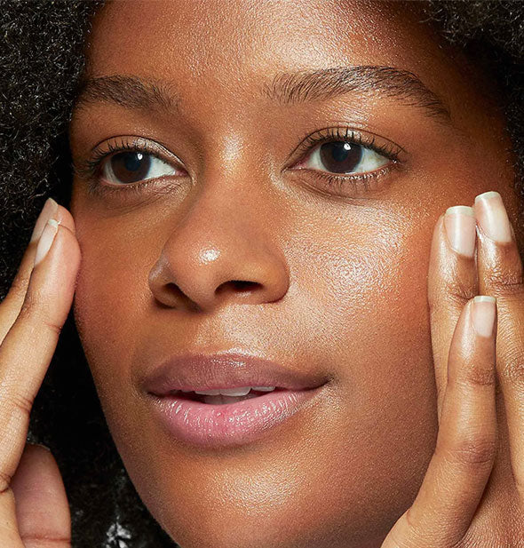 Model smooths serum into cheeks with fingertips