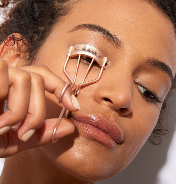 Model demonstrates use of a rose gold eyelash curler