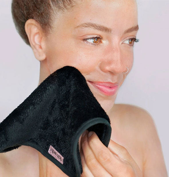 Model holds a black microfiber cloth to cheek