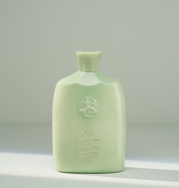 Light green bottle of Oribe Cleansing Crème for Moisture & Control on a gray background