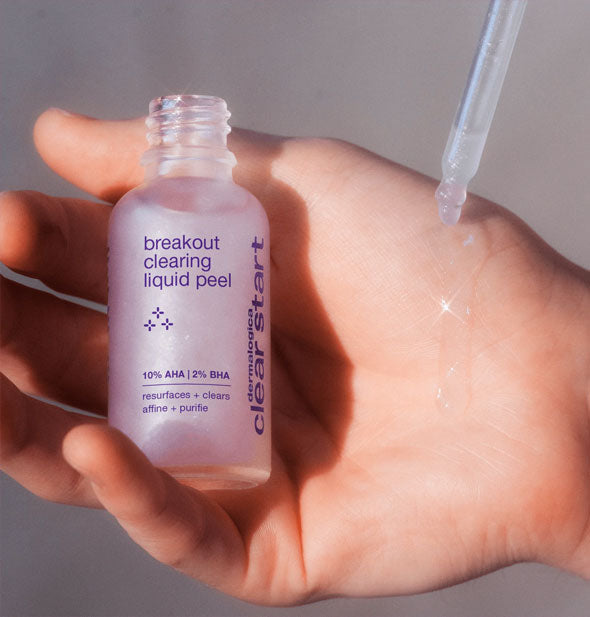 Model holds a bottle of Dermalogica Clear Start Breakout Clearing Liquid Peel in hand and applies product to skin with the dropper applicator