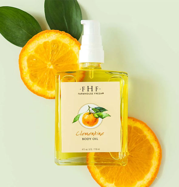Bottle of FarmHouse Fresh Clementine Body Oil staged with slices of orange