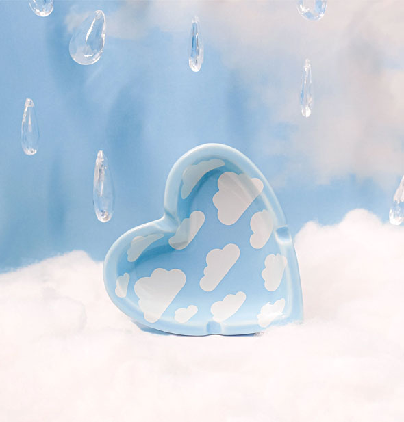 Heart shaped clouds ashtray rests on a puffy white surface with crystal raindrops staged behind