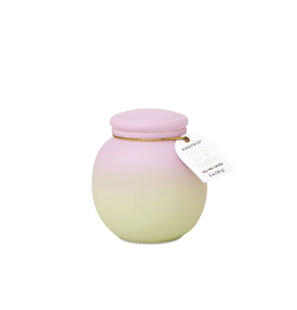 Rounded candle jar with frosted matte finish and green-to-pink ombre coloration is topped with a lid and tag on a gold band