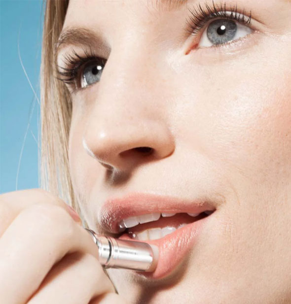 Model applies lip balm to lower lip