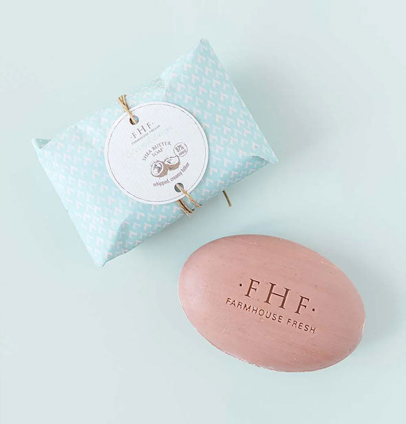 Dark pink bar of stamped FarmHouse Fresh Coconut Cream Shea Butter Soap with printed blue packaging tied in hemp string