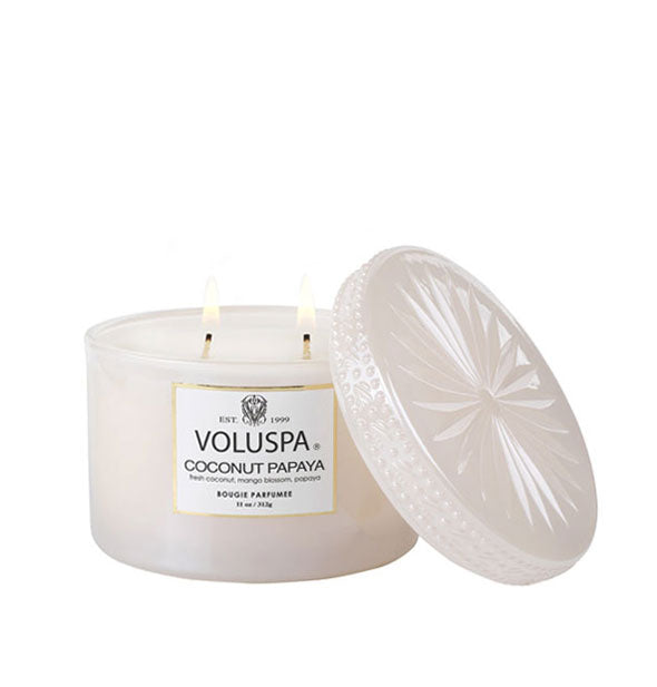 Cream-colored glass jar 2-wick Voluspa candle with embossed lid set to the side