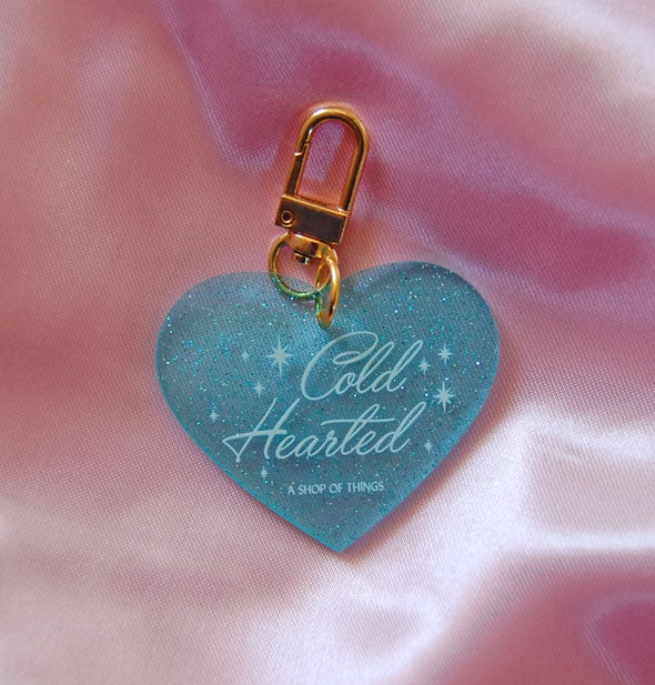 Blue glitter heart-shaped keychain with gold clasp says, "Cold Hearted" in white script lettering with star accents