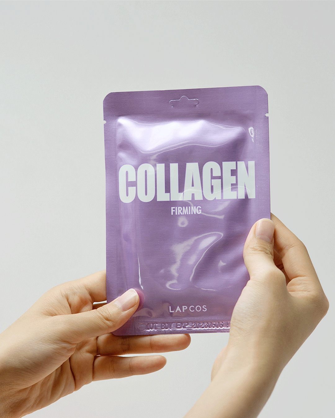 Model's hands open a Collagen Firming sheet mask packet and unfold the mask inside