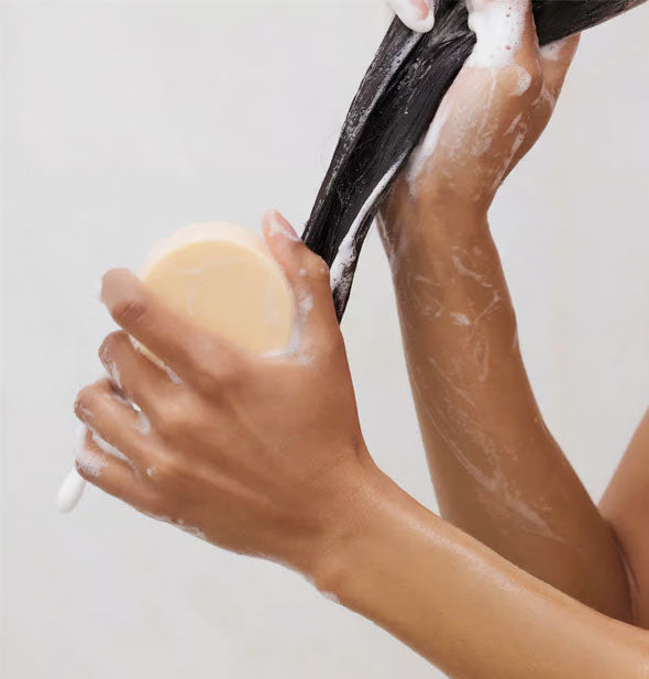Model demonstrates use of a conditioning bar on wet hair