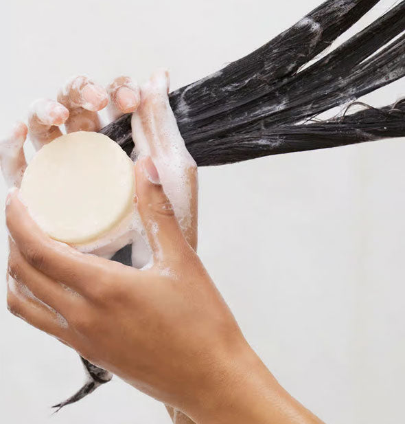 Model demonstrates use of a solid conditioner bar on wet hair