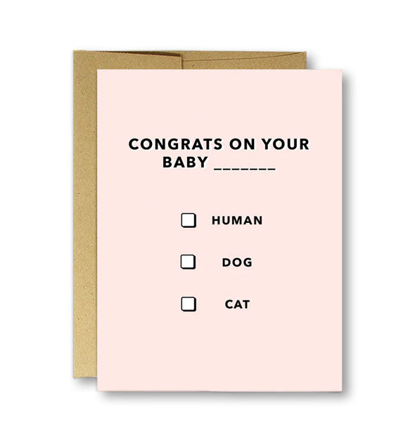 Blush pink greeting card on top of kraft envelope says, "Congrats on your baby ___" with checkboxes for Human, Dog, and Cat underneath