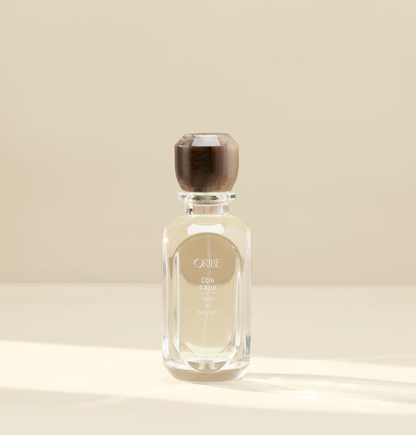 Clear glass bottle of Oribe Côte d'Azur Eau de Parfum with brown marbled-effect lid