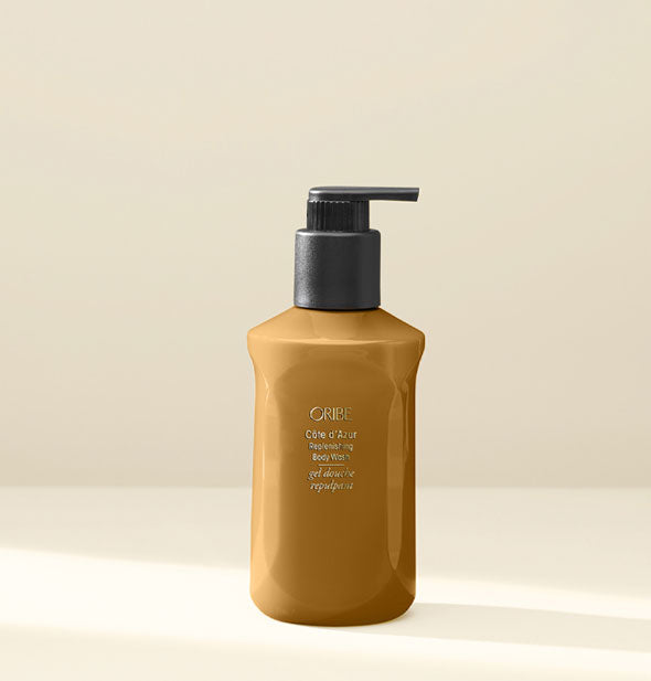 Bronze-colored faceted bottle of Oribe Côte d'Azur Replenishing Body Wash with black pump nozzle