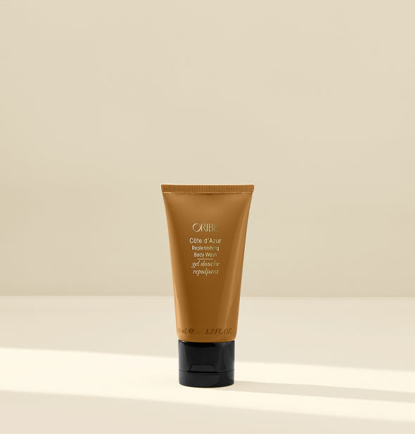 Bronze-colored travel-size bottle of Oribe Côte d'Azur Replenishing Body Wash with black cap