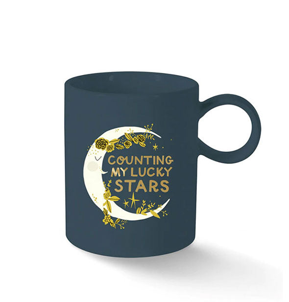 Dark blue coffee mug with circular handle says, "Counting my lucky stars" in gold lettering inside a crescent moon illustration