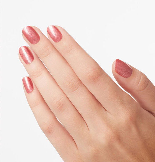 Model's hand wears a shimmery muted pink shade of nail polish