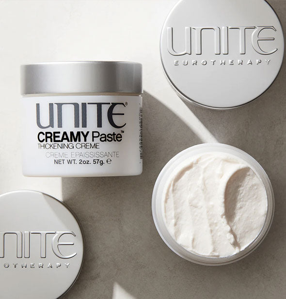 Pots of Unite CREAMY Paste, one of which is opened to show product inside from the top