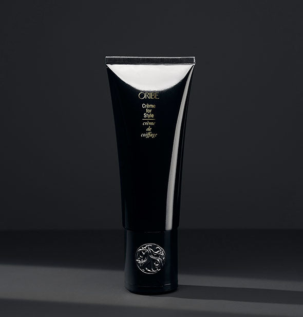 Black bottle of Oribe Crème for Style on dark gray background