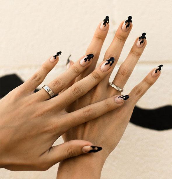 A model wears Crystal Flame press-on nails by Rave Nailz featuring a clear surface with painted black flames.