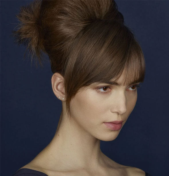 Model with voluminous bouffant updo against a blue background