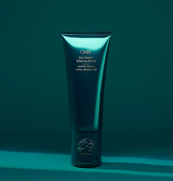 Dark green bottle of Oribe Curl Control Silkening Crème on matching background