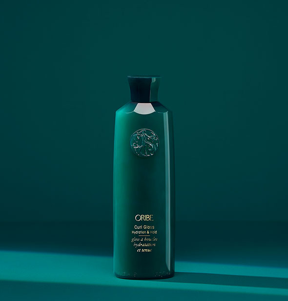 Dark teal bottle of Oribe Curl Gloss: Hydration & Hold on matching background
