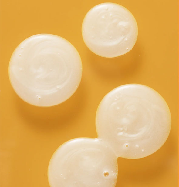 Droplets of white pearlescent shampoo on an orange surface