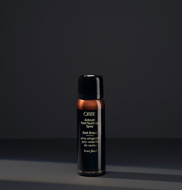 Small can of Oribe Airbrush Root Touch-Up Spray in the shade Dark Brown on a dark background