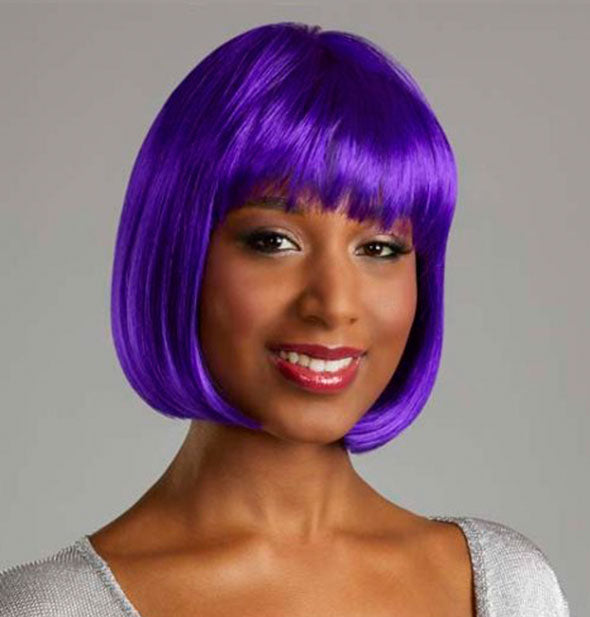 Model wearing a short, purple wig with bangs.