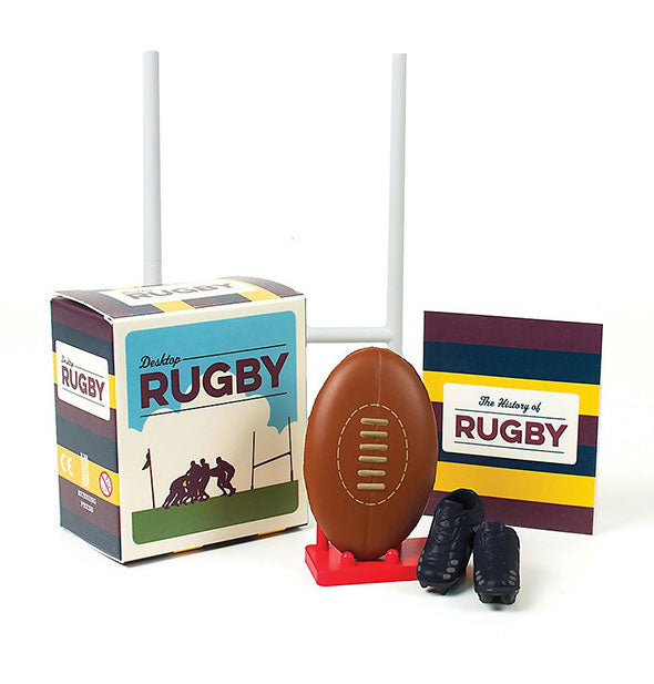 Contents of the Desktop Rugby Kit: white goalpost, miniature football, miniature black cleats, booklet, and box