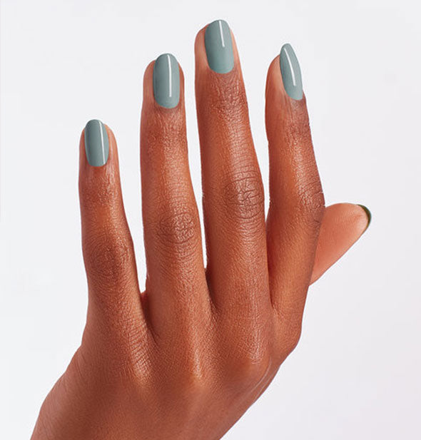 Model's hand wears a grayish-greenish-blue shade of nail polish