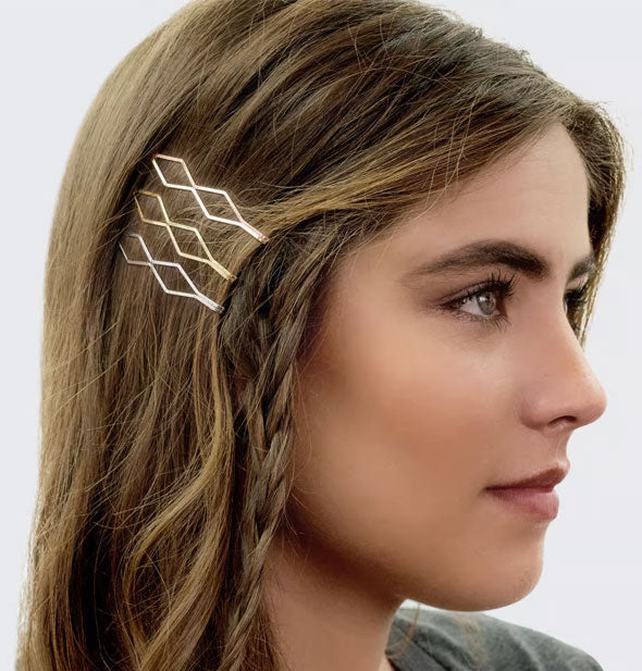Model wears three metallic diamond-shaped bobby pins in a side-swept style with messy braid