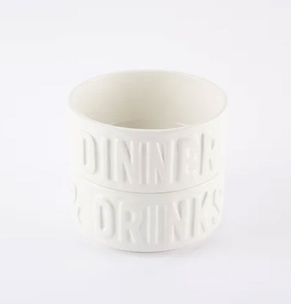 Two stacked white ceramic bowls: one says "Dinner" and the other says "Drinks" in raised lettering