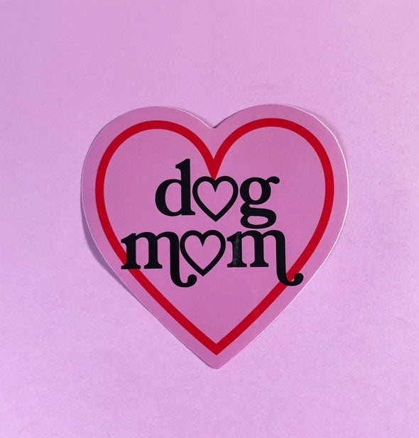 Pink heart-shaped sticker with red outline says, "Dog Mom" in black lettering with heats where the Os should be