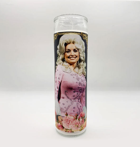 Tall glass prayer-style candle with image of smiling Dolly Parton in a pink dress accented with pink flowers at the bottom