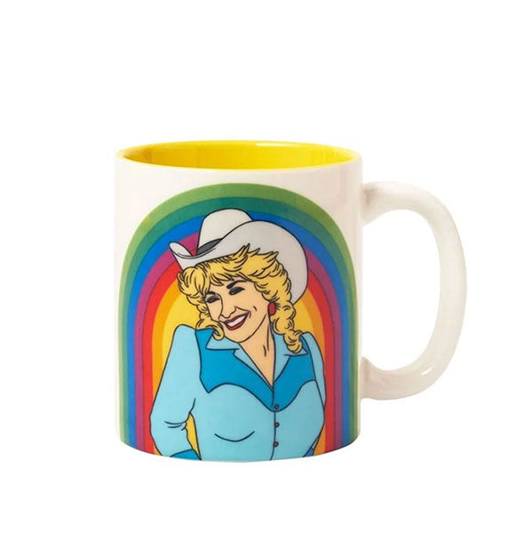 White coffee mug with yellow interior features an illustration of Dolly Parton wearing a cowboy hat in front of a colorful rainbow design