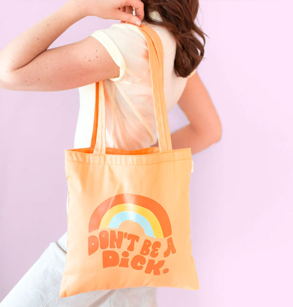 Model wears an orange Don't Be a Dick tote bag over shoulder