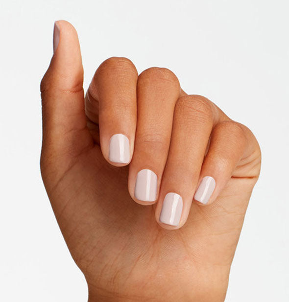 Model's hand wears a light dusty pink shade of nail polish
