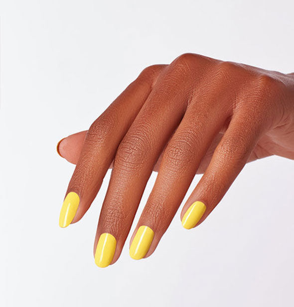 Model's hand wears a yellow shade of nail polish