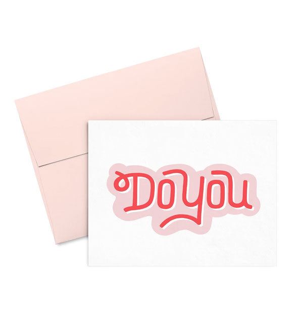 Rectangular white greeting card says, "Do You" in pink and red lettering and includes a blush pink envelope