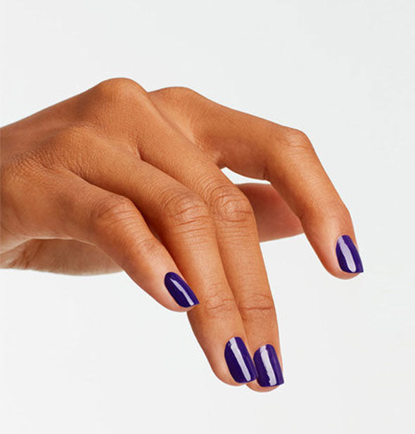Model's hand wears a dark indigo shade of nail polish