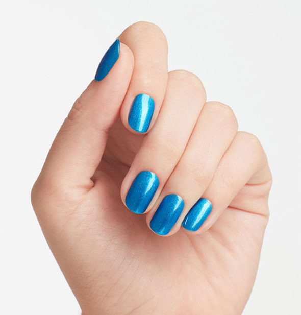 Model's hand wears a shade of shimmering blue nail polish