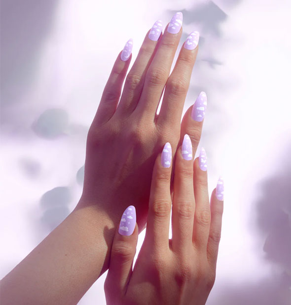 Model's hands are wearing purple press-on nails with white cloud, star, and moon design