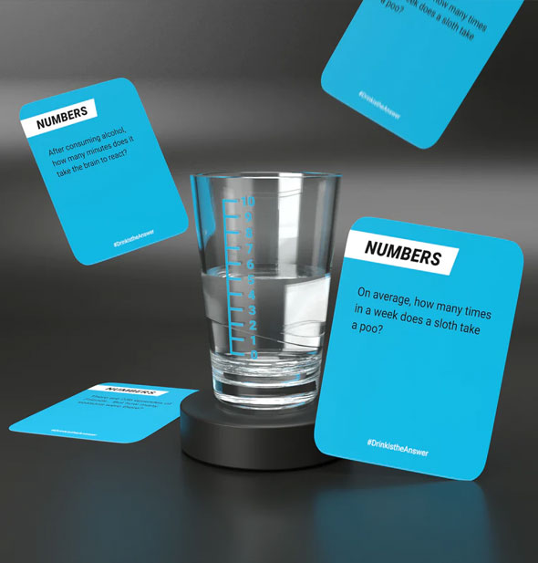 Sample cards from Drink Is the Answer! and half-filled shot glass with numbered blue measurement lines
