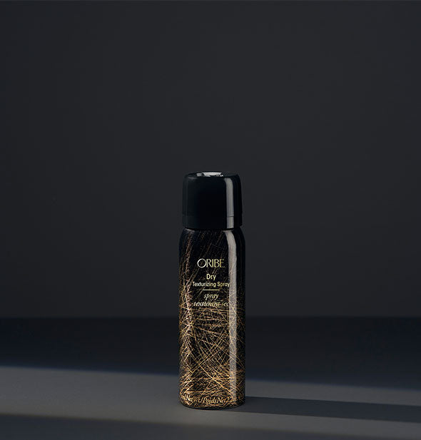 Small black and gold can of Oribe Dry Texturizing Spray on dark gray background