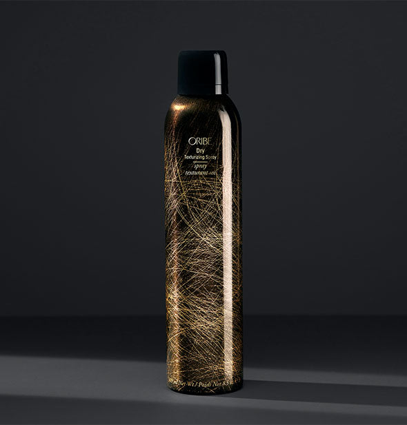 Black and gold can of Oribe Dry Texturizing Spray on dark gray background